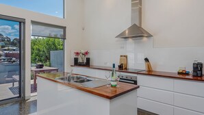 Una cocina moderna con una isla central, pileta de acero inoxidable y campana extractora integrada.