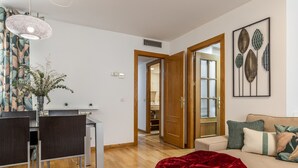 Uma sala de estar moderna com um sofá, um cobertor vermelho e um espaço de jantar com mesa e cadeiras.