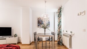 Uma sala de estar moderna com área de jantar, televisão de tela plana, manta vermelha e uma planta decorativa.