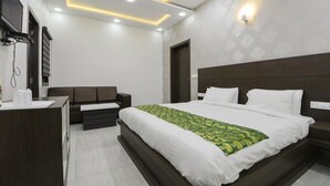 A modern hotel room with a large bed, a desk, and a sofa. - Hotel Rigal inn (Agra)