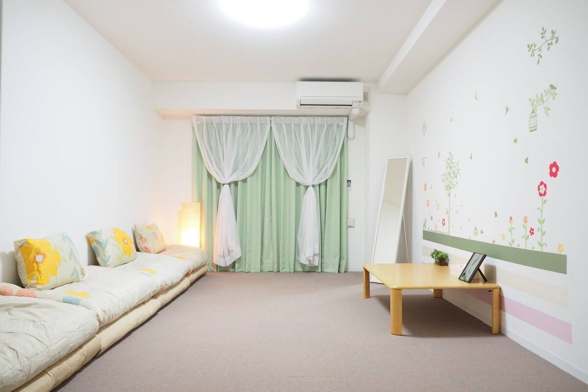 Ein Schlafzimmer mit Bett, Nachttisch, Spiegel und einer Wand mit floralen Aufklebern.