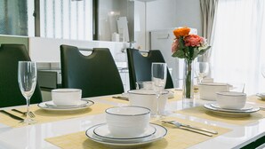 A dining table set with white plates, bowls, and glasses, accompanied by a vase of flowers. - Sea Sunset Villa (Motobu)