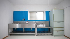 Eine kleine Küchenzeile mit Spüle aus Edelstahl, einem Gasherd und einem hellblauen Kühlschrank.