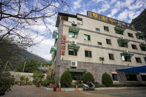 A multi-story hotel with a stone facade, multiple windows, and a sign indicating it is a hotel. - Xiangting homestay (Puli)