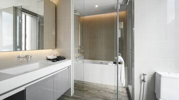 Une salle de bain moderne avec une douche à parois de verre, une baignoire blanche et un grand miroir au-dessus du meuble-lavabo.