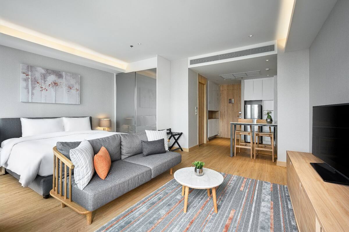 Ein modernes Hotelzimmer mit Bett, Sofa, Essbereich und Fernseher.