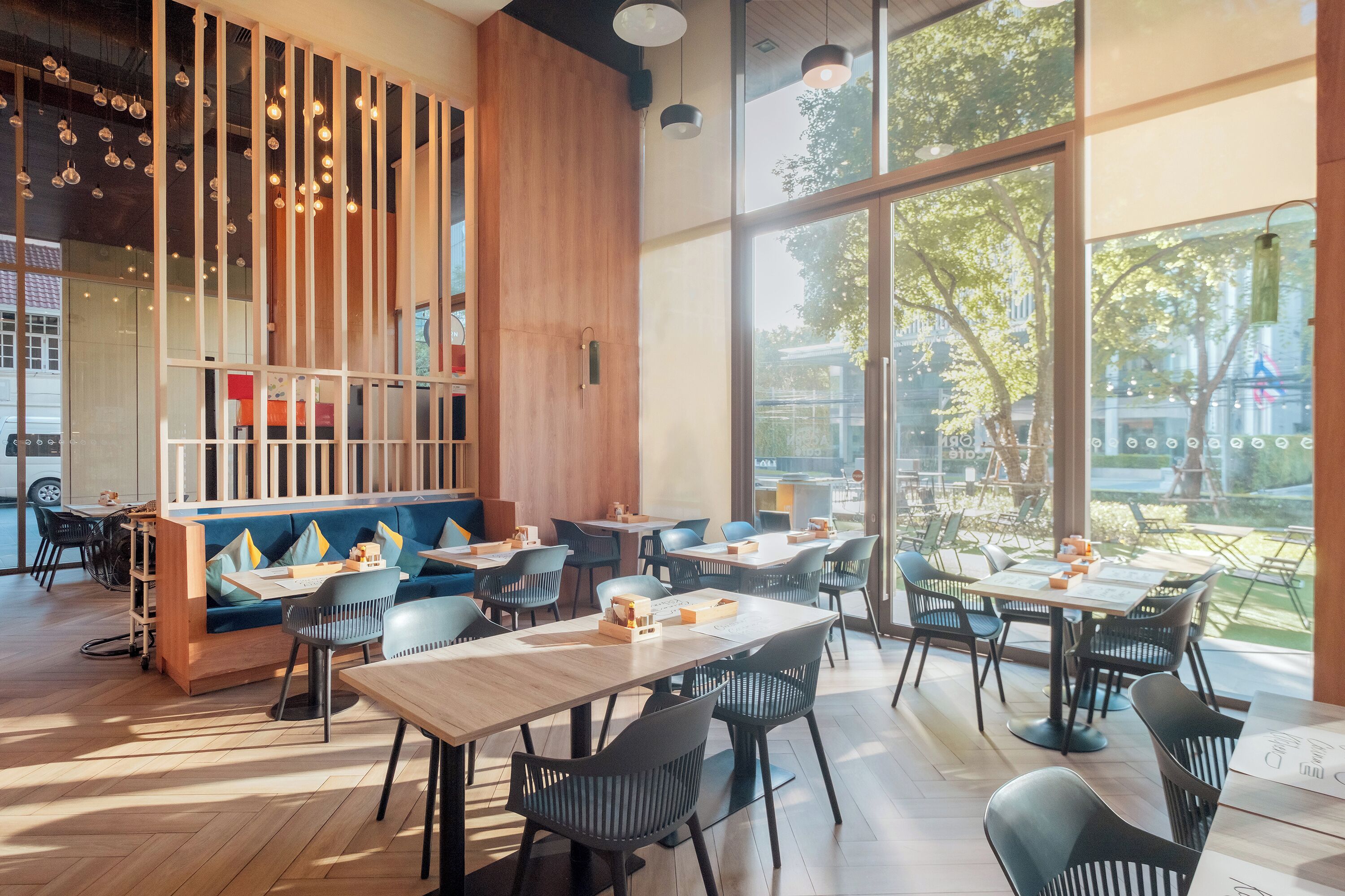 A modern restaurant interior with wooden accents, large windows, and a mix of seating options.