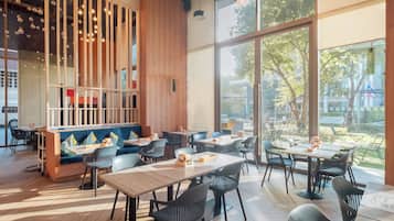 A modern restaurant interior with wooden accents, large windows, and a mix of seating options.