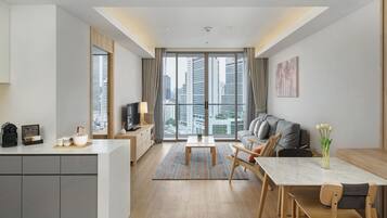A modern living room with a sofa, dining table, and kitchen area.