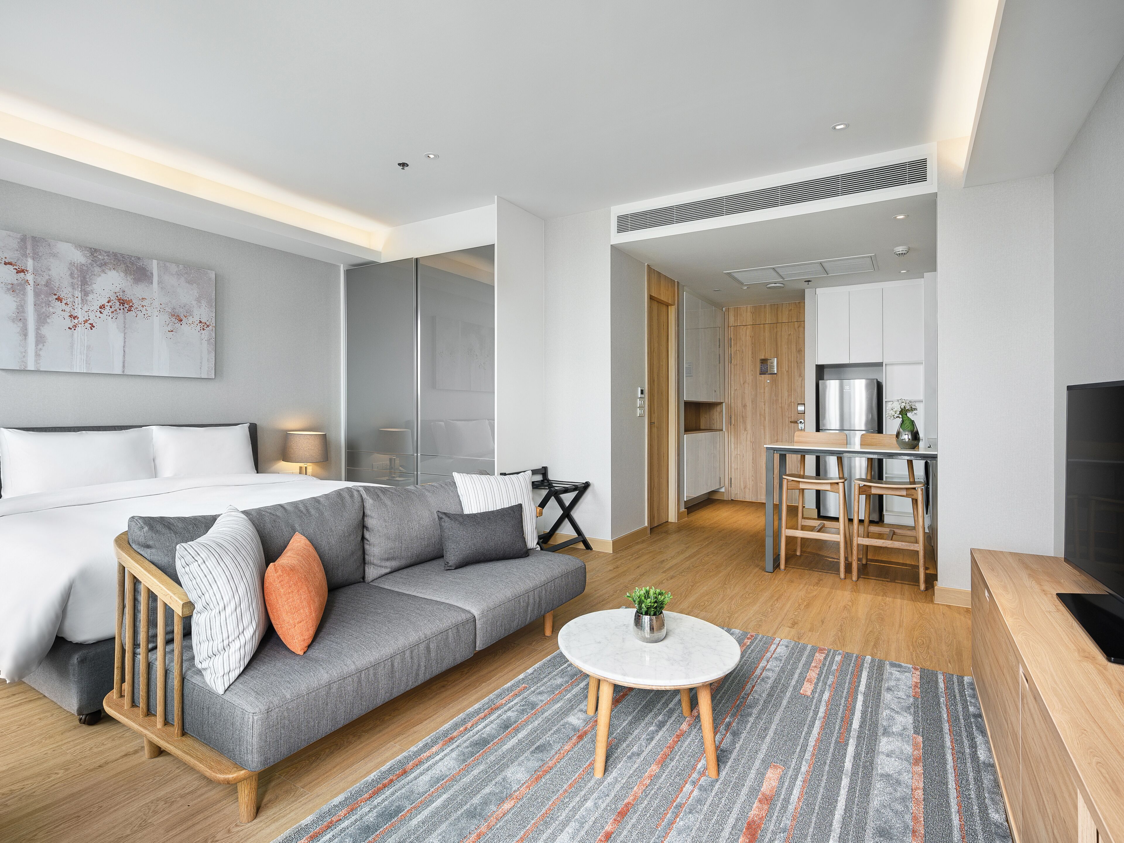 Une chambre d’hôtel moderne équipée d’un lit, d’un canapé, d’une table à manger et d’un coin cuisine.