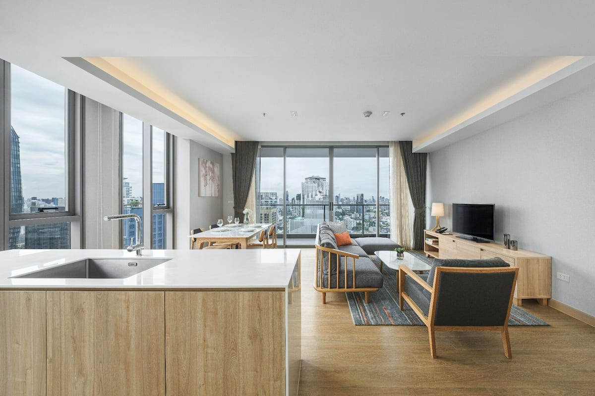 Eine moderne Wohnung mit Küche, Essbereich und Wohnzimmer, ausgestattet mit großen Fenstern und Blick auf die Stadt.
