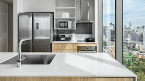 Een moderne keuken met een roestvrijstalen koelkast, een magnetron, een fornuis en een groot raam met uitzicht over de stad.