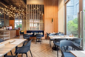 A modern restaurant interior with wooden floors, black chairs, and a bar area. - Oakwood Suites Bangkok (Bangkok)