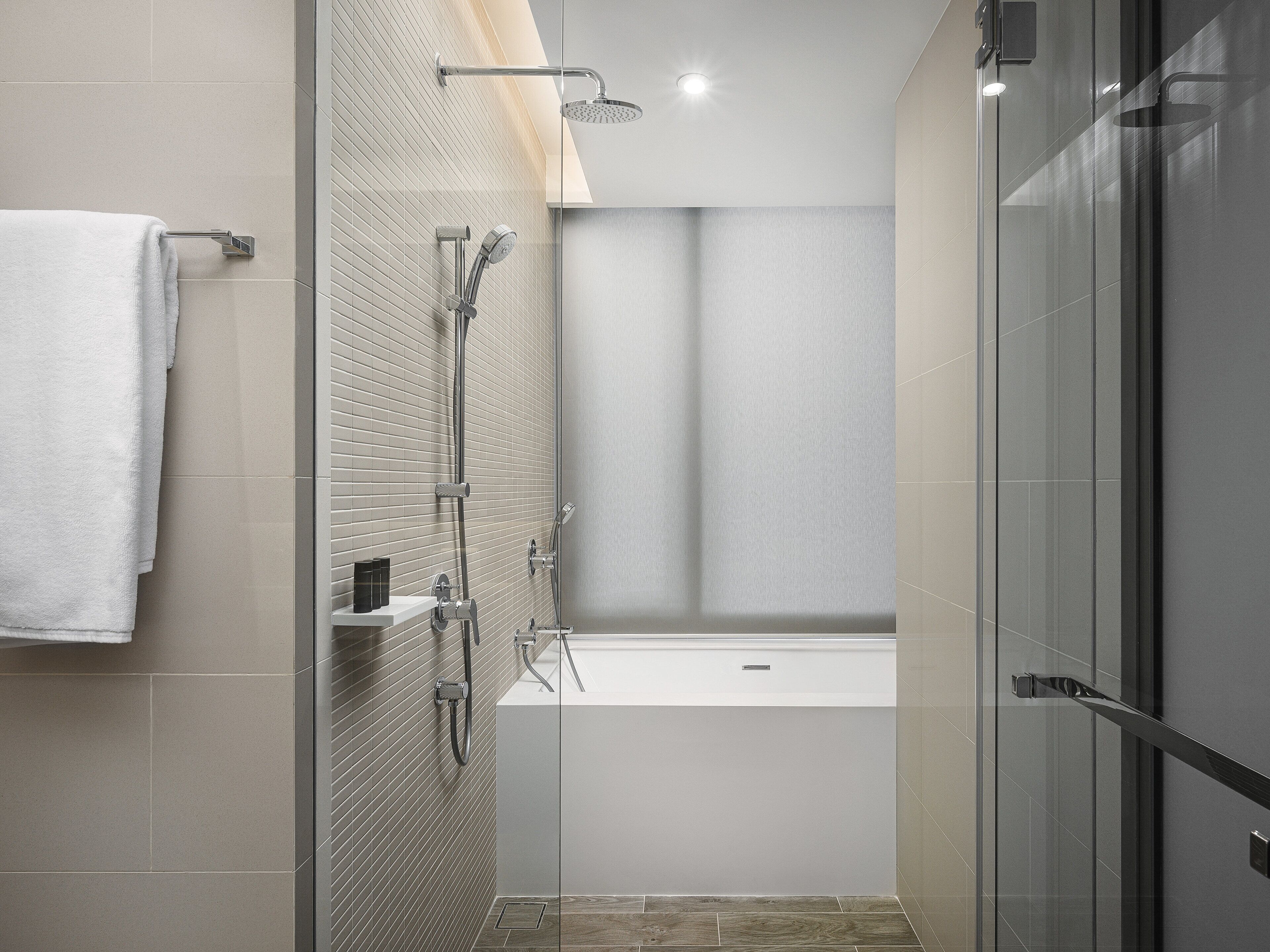 Un baño moderno con ducha de vidrio, una bañera blanca y un perchero para toallas.
