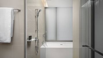 Un baño moderno con ducha de vidrio, una bañera blanca y un perchero para toallas.