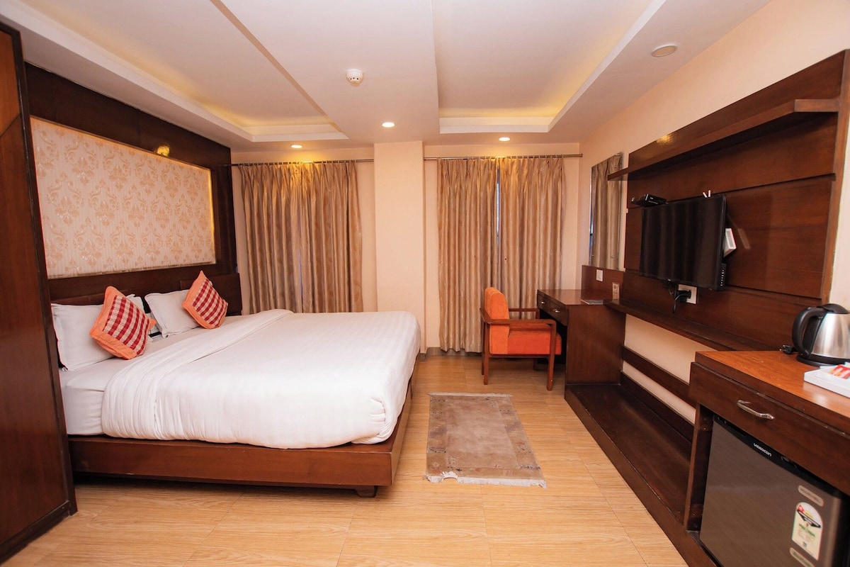 A hotel room with a bed, a desk, a chair, a television, and a coffee maker.