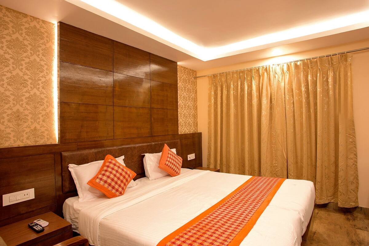 A hotel room with a large bed, wooden headboard, and a nightstand with a remote control.