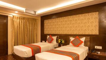A hotel room with two beds, a wooden headboard, a nightstand with a phone, and a wall-mounted air conditioner.