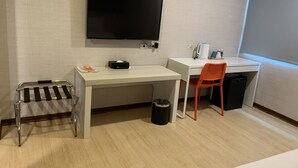 A hotel room with a desk, a television mounted on the wall, a small trash bin, and a window with a view. - Hatago+  The Alley (Taipei)