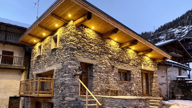 A stone building with wooden balconies and a staircase leading to the entrance.