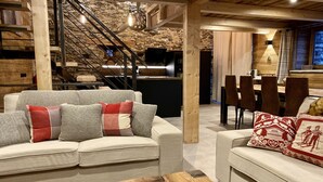 A cozy living area with a sofa set, wooden coffee table, and a staircase leading to an upper level.