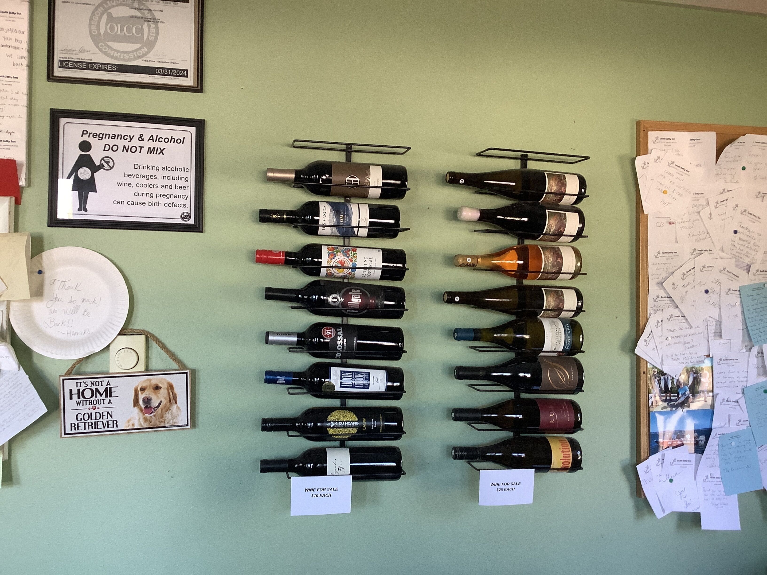 Eine Wand mit verschiedenen Weinflaschen, einem Hinweis zum Thema Schwangerschaft und Alkohol sowie Schildern, die Wein zu Preisen von 10 und 25 Dollar anbieten.