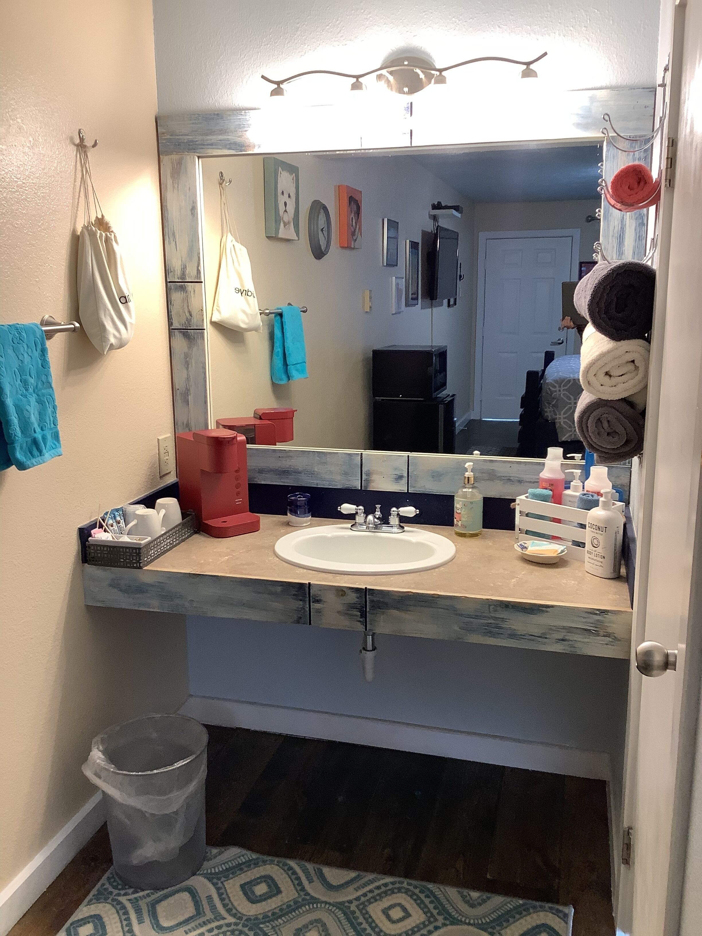 Une salle de bain équipée d’un lavabo, d’un miroir et de divers produits de toilette.
