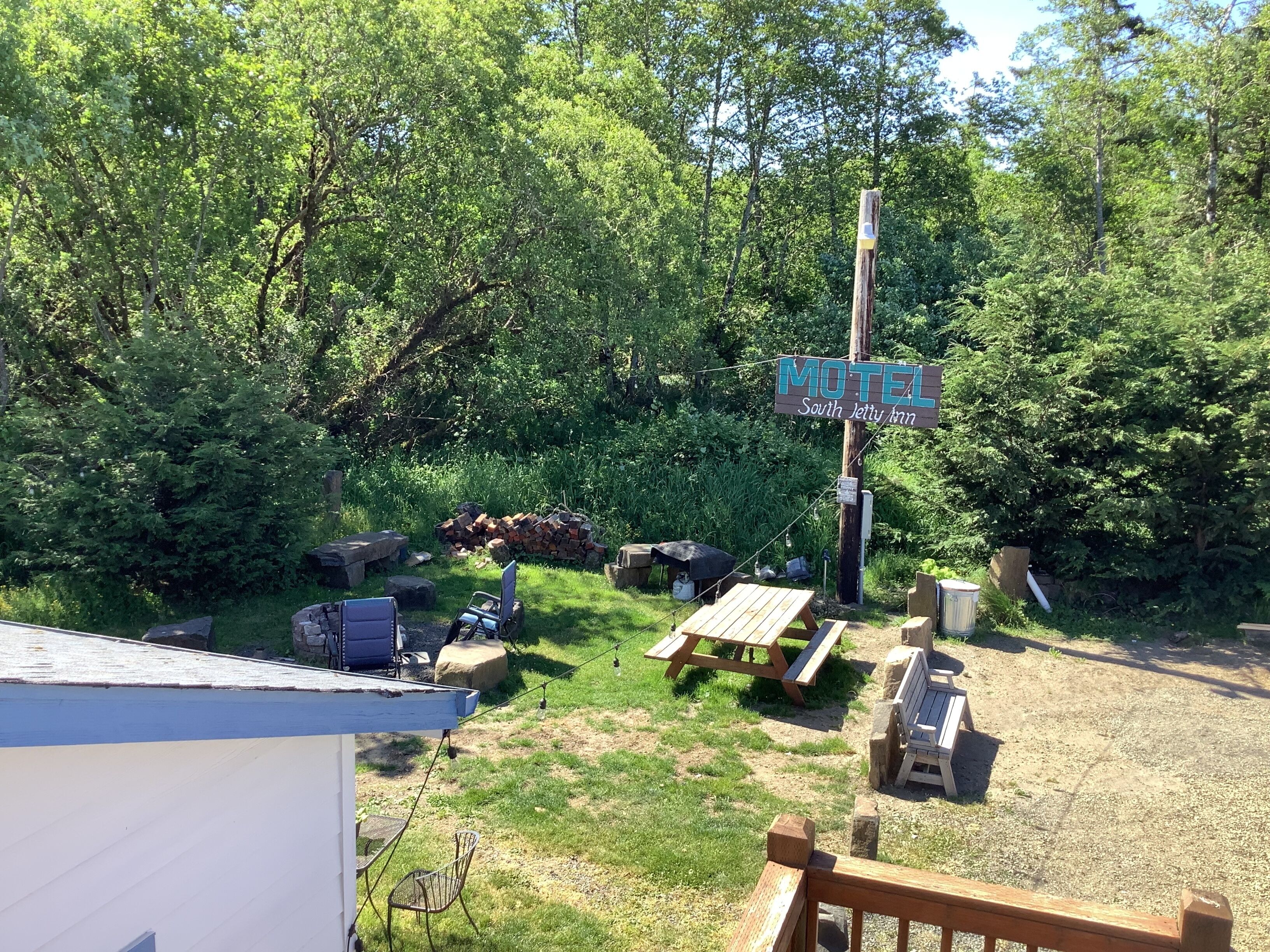 En skylt för ett motell, med ett picknickbord och stolar placerade på en gräsyta omgiven av träd.