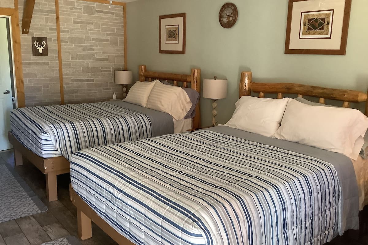 Two single beds with striped bedding, wooden headboards, and nightstands with lamps.