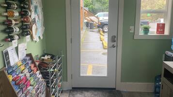 A room with a door leading outside, a shoe display, and a window with a view of the outside.