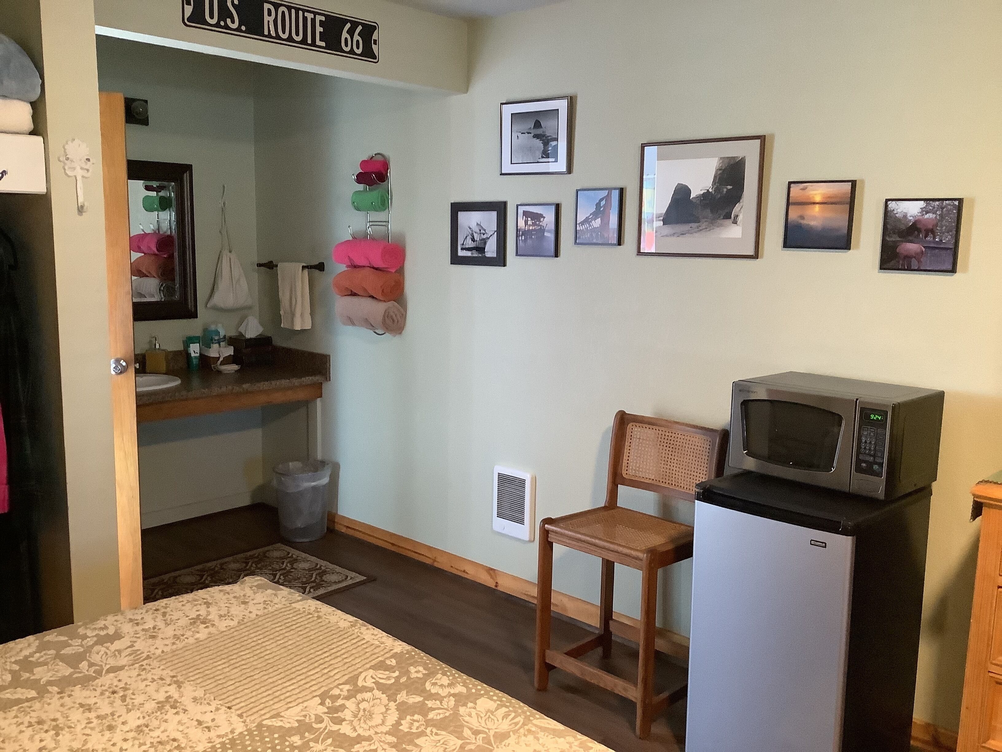 A compact kitchen with a microwave, a small refrigerator, a wooden chair, and a sink.