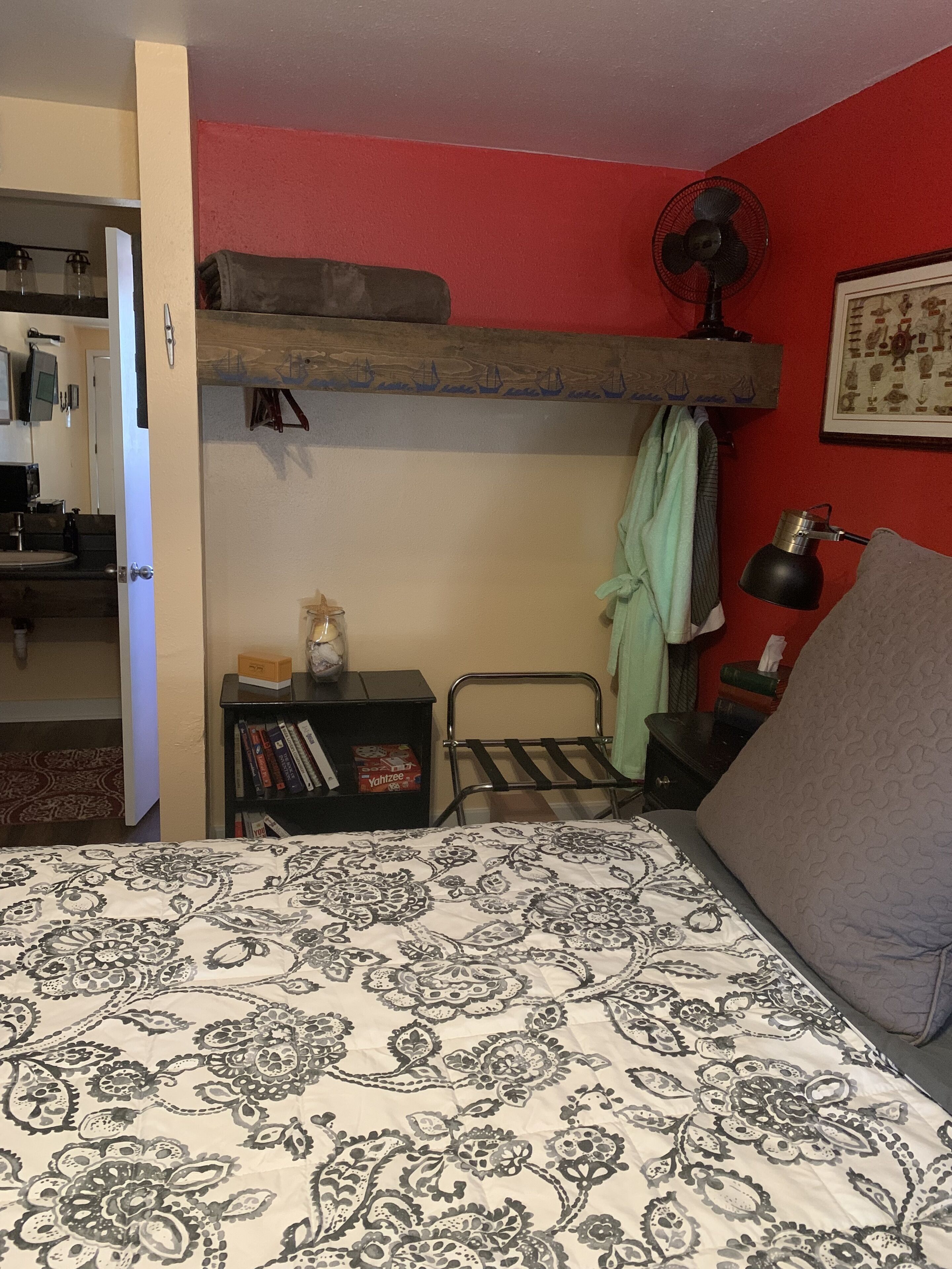 Un dormitorio con literas, una mesita de noche con libros, un ventilador y una lámpara.