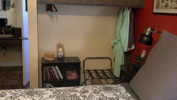 Un dormitorio con literas, una mesita de noche con libros, un ventilador y una lámpara.
