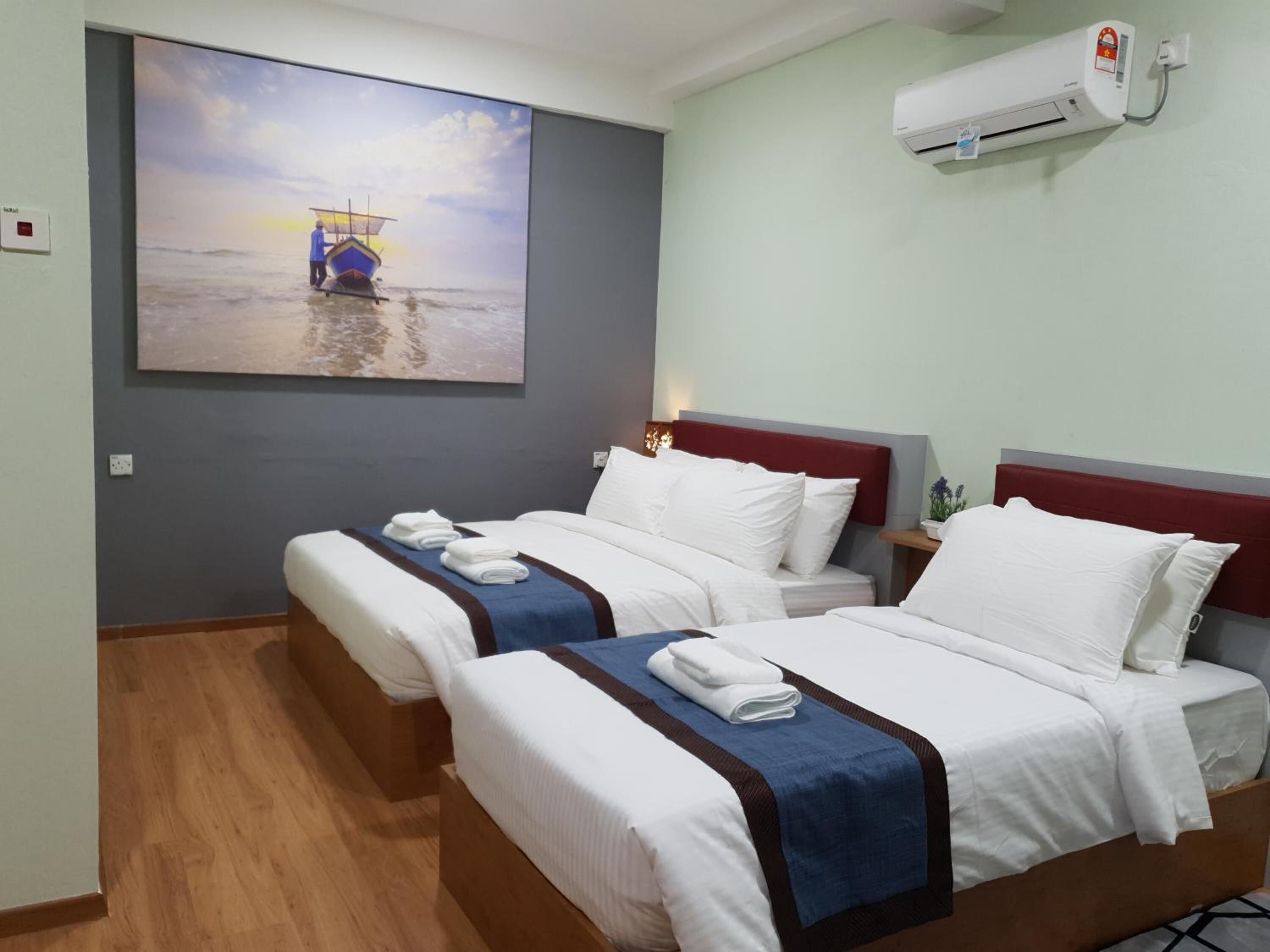 A hotel room with two beds, a painting of a boat on water, and an air conditioning unit.