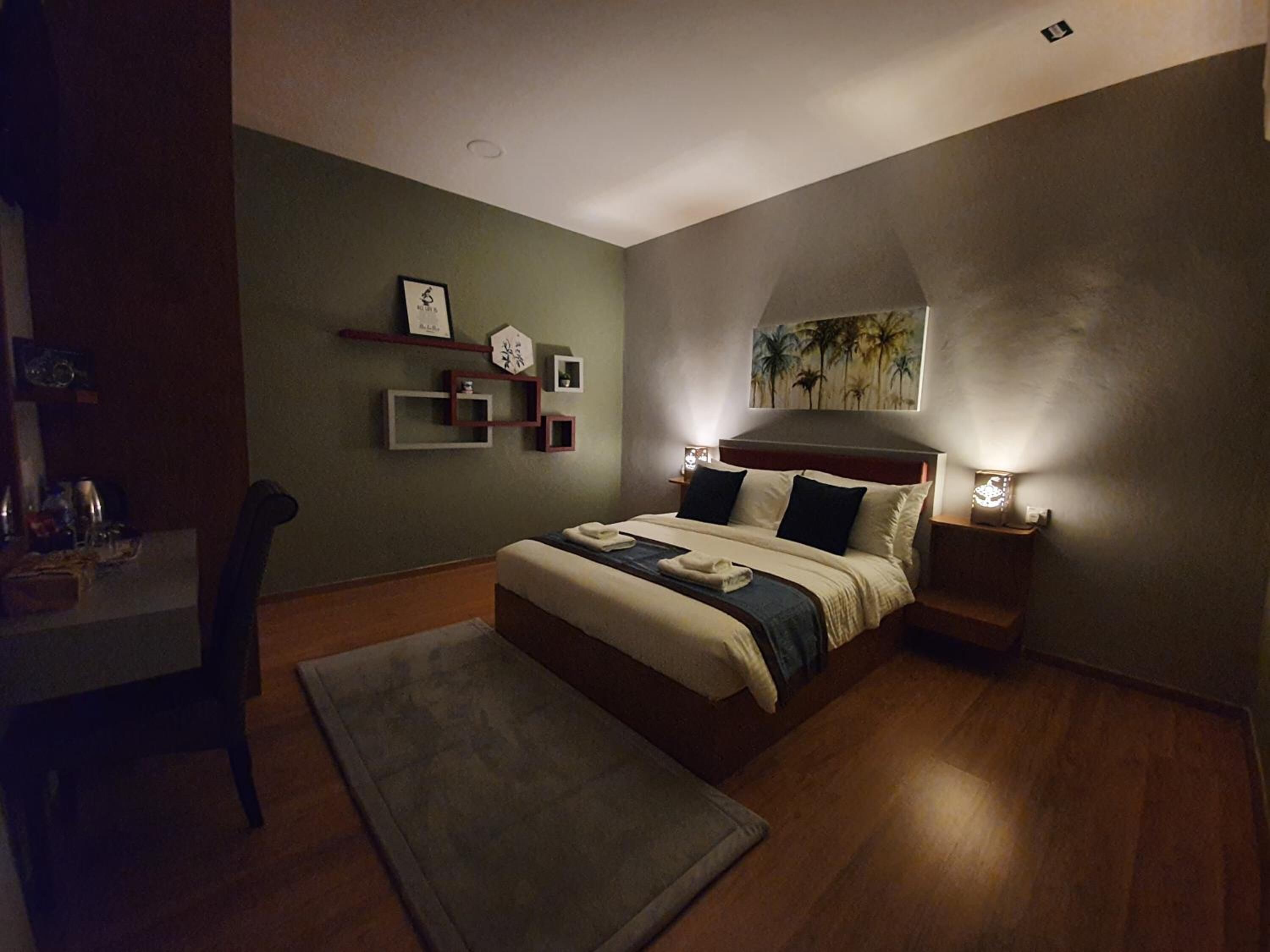 Un dormitorio moderno con una cama grande, lámparas de noche, un escritorio y una silla.