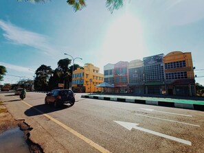 A street with buildings, a motorcycle, and a car. - Assalam Hotel (Kota Bharu)