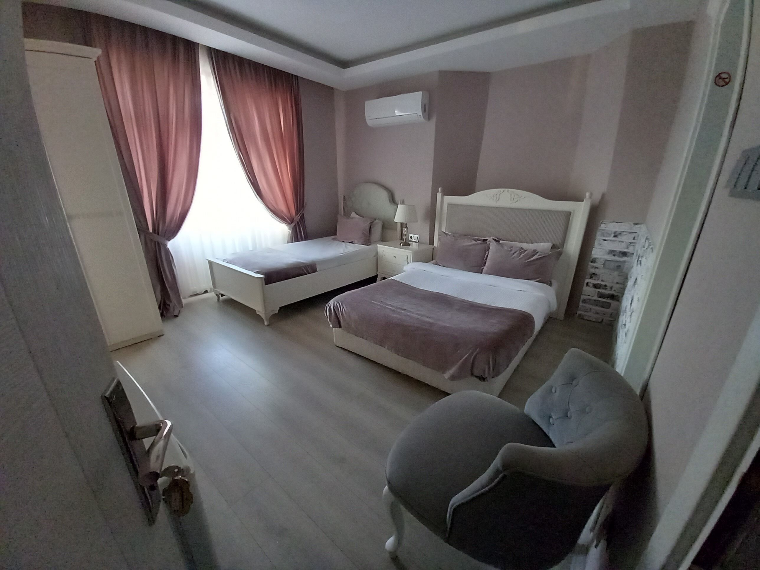 A bedroom with a bed, a chair, a nightstand, and an air conditioning unit.