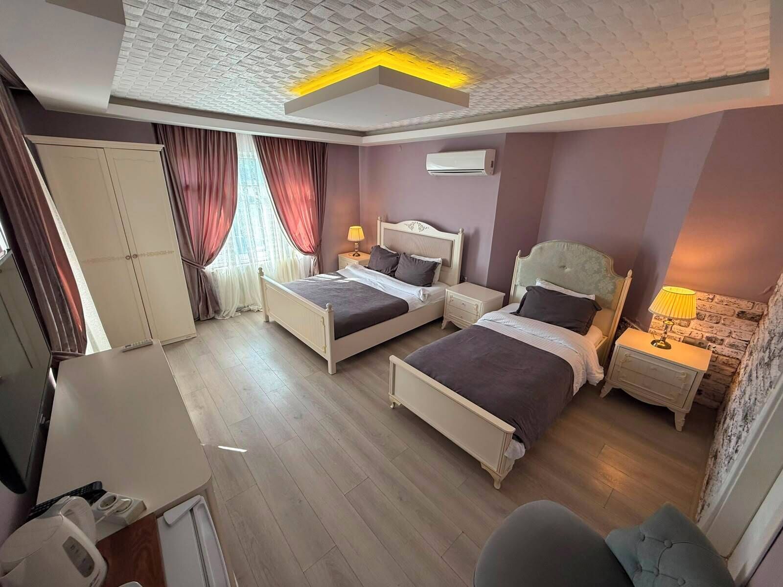 Hotellihuone, jossa on kaksi sänkyä, vaatekaappi, työpöytä ja tuoli.
