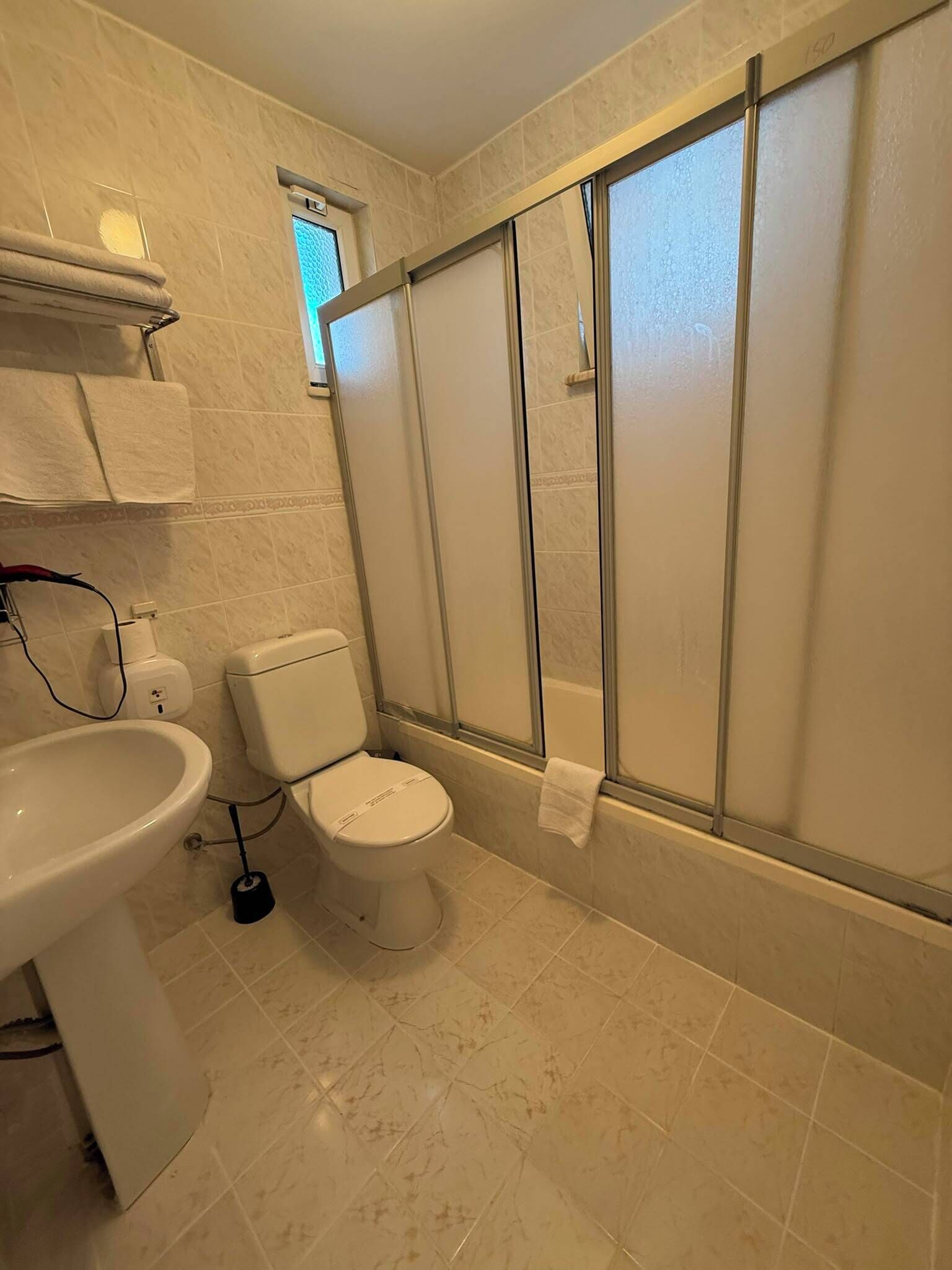 A bathroom with a toilet, sink, and shower area.