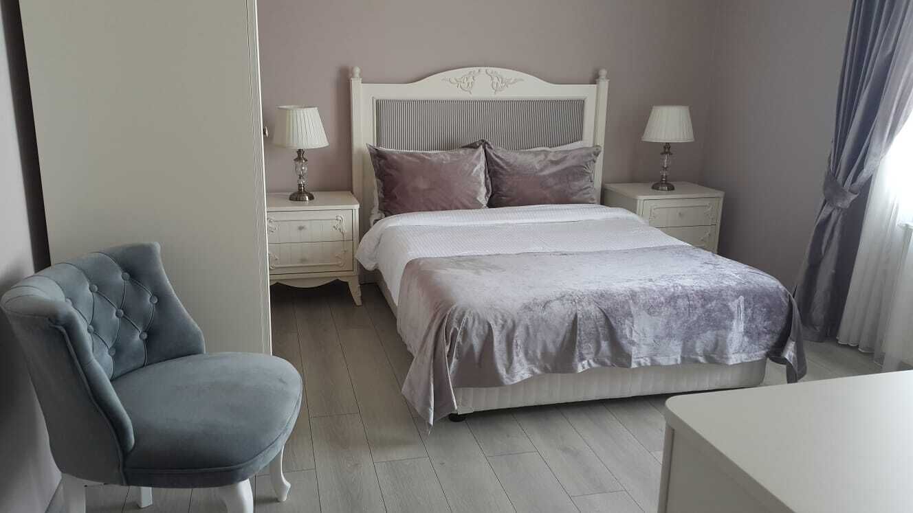 A bedroom with a bed, two bedside tables, a chair, and a nightstand.