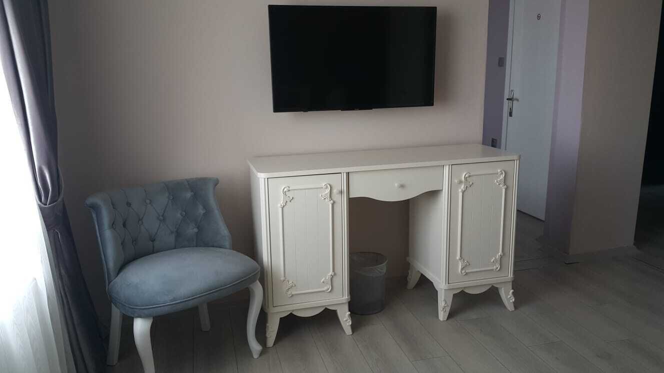 A room with a white cabinet, a blue chair, and a television on the wall.