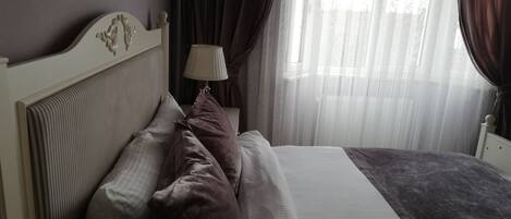 Una cama bien tendida con cabecera, almohadas y manta.