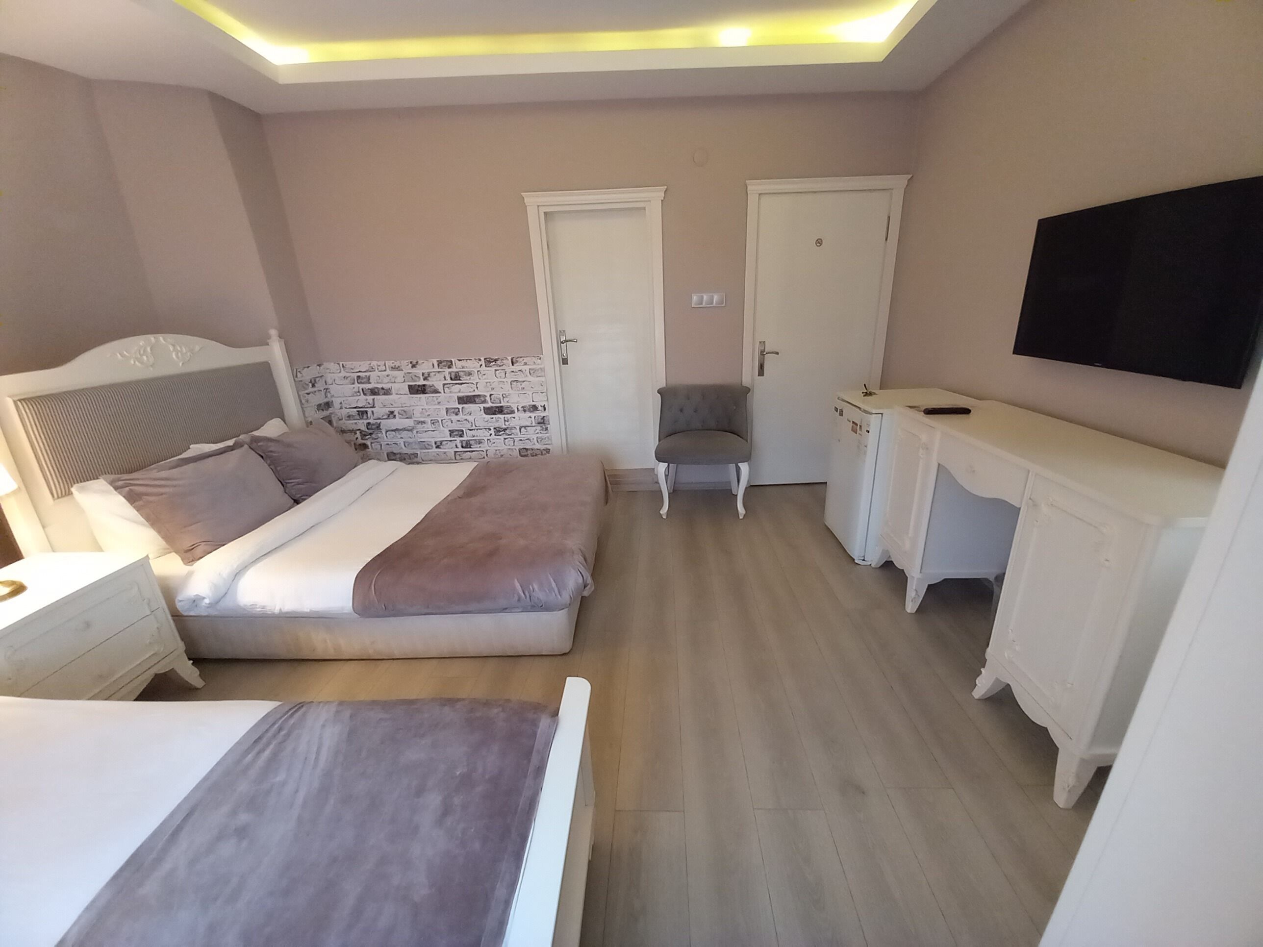 A bedroom with a bed, a desk, a chair, and a TV.