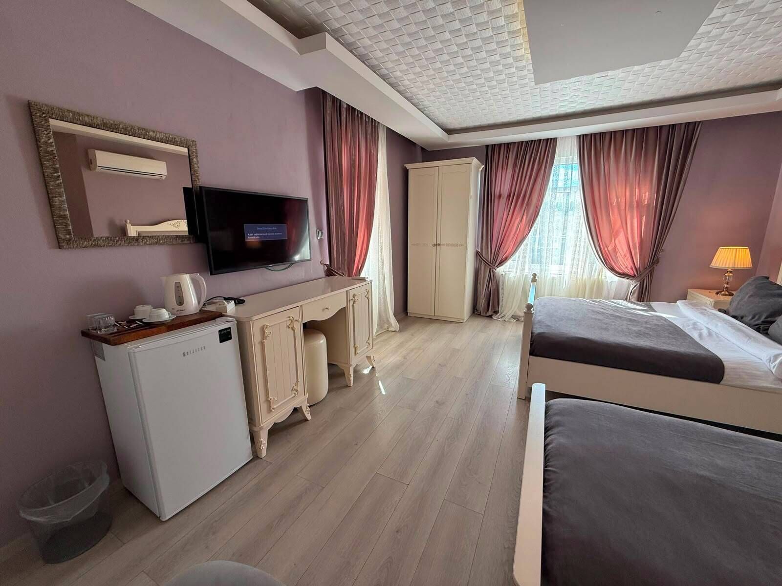 A hotel room with a bed, a desk with a computer, a television, and a wardrobe.