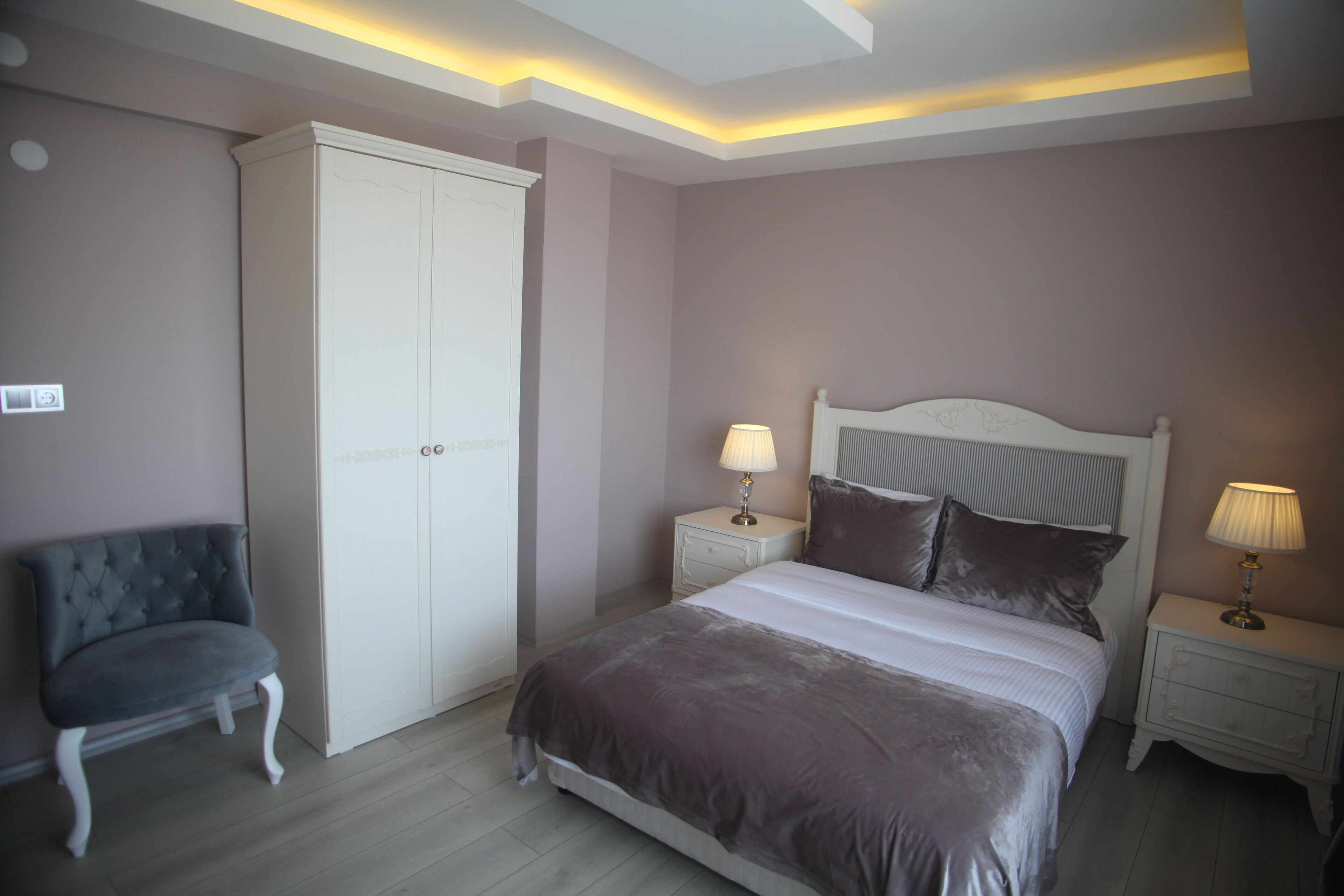 A bedroom with a bed, nightstands, a wardrobe, and a chair.
