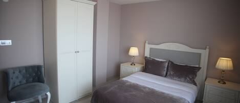 A bedroom with a bed, nightstands, a wardrobe, and a chair.