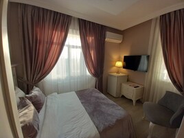 A hotel room with a bed, a TV, a nightstand, and a chair.