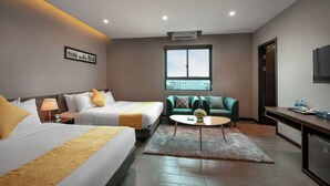 Une chambre d’hôtel avec deux lits, un canapé, une petite table et un téléviseur.