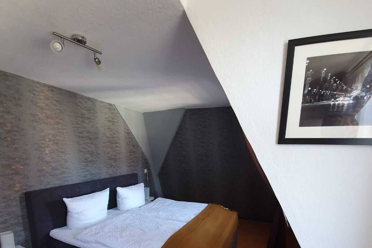 A modern bedroom with a large bed, a white chair, and a framed picture on the wall.