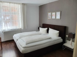 A double bed with white bedding, a headboard, and a bedside table with a lamp.